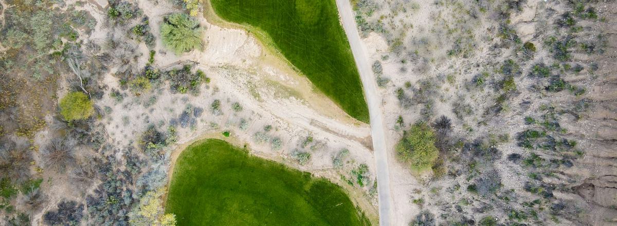 Aerial view of a green golf course fairway winding through Arizona desert landscape