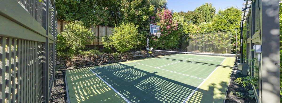 An empty outdoor court with a net on a sunny day, framed by trees