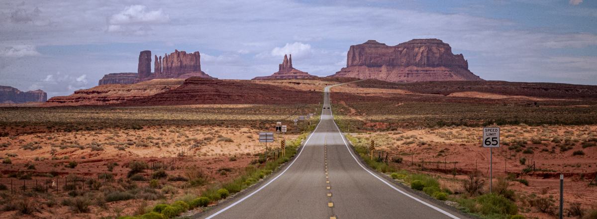 A long straight road leading toward the red buttes of Monument Valley