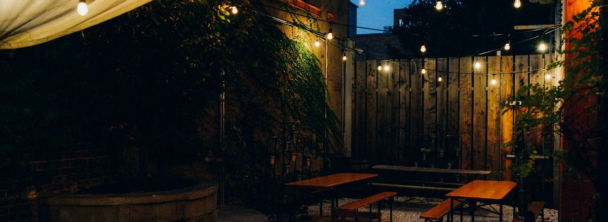 An outdoor patio with string lights glowing at dusk
