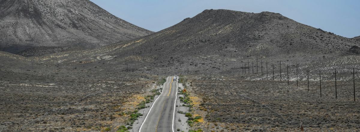 A two-lane road winding toward desert mountains
